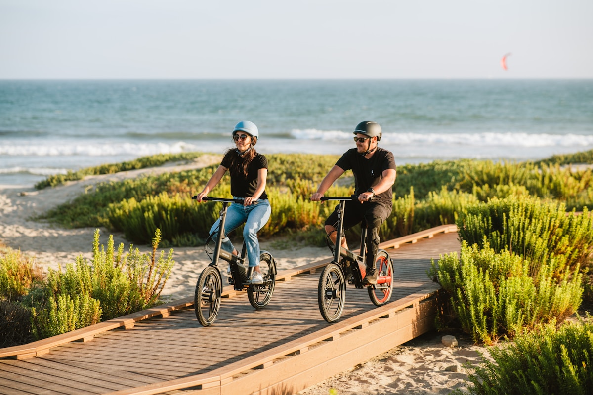 Casal passeando de bicicleta em um calçadão junto à praia